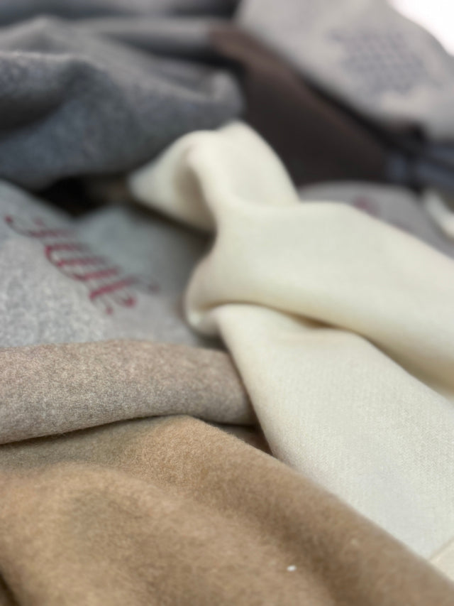 Kearsley 100% Mongolian cashmere, Italian-woven in Camel, Silver Gray, Charcoal, Espresso, Café Au Lait, Vanilla, and Wolf, stacked with embroidered knot logos.