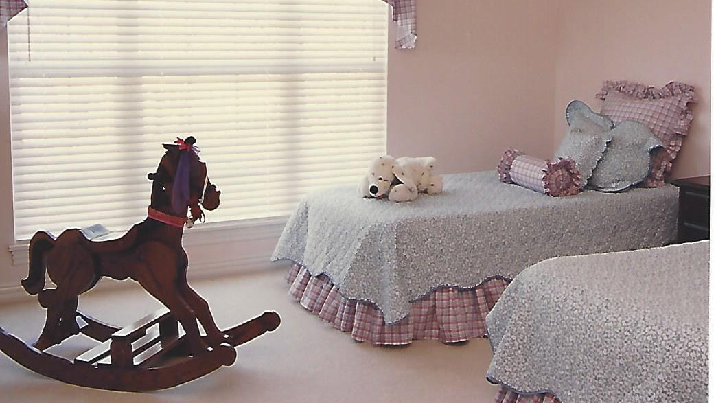Kearsley Design created this lovely little girls interior with a beautiful plaid and quilted coverlets with soft pink walls and soft light with an heirloom rocking horse. 