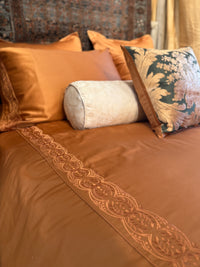 Rich cognac/brown duvet cover and Pillowcases with Tyrollean Embrdoeiry in matching tyrollean color.  Intricate beautiful rich embroidery  Anqtique Silk pillows in green and champagne with taupe bolster.  