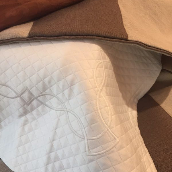 A close up of a Kearsley Pillow sham with Kearsley Moulding embroidery Ivory on ivory and Kearsley Carneros Heavy LInen block stripe pillowsham